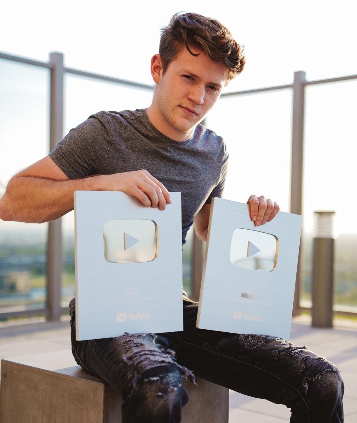 Caleb Boxx holding two YouTube Silver Play Buttons